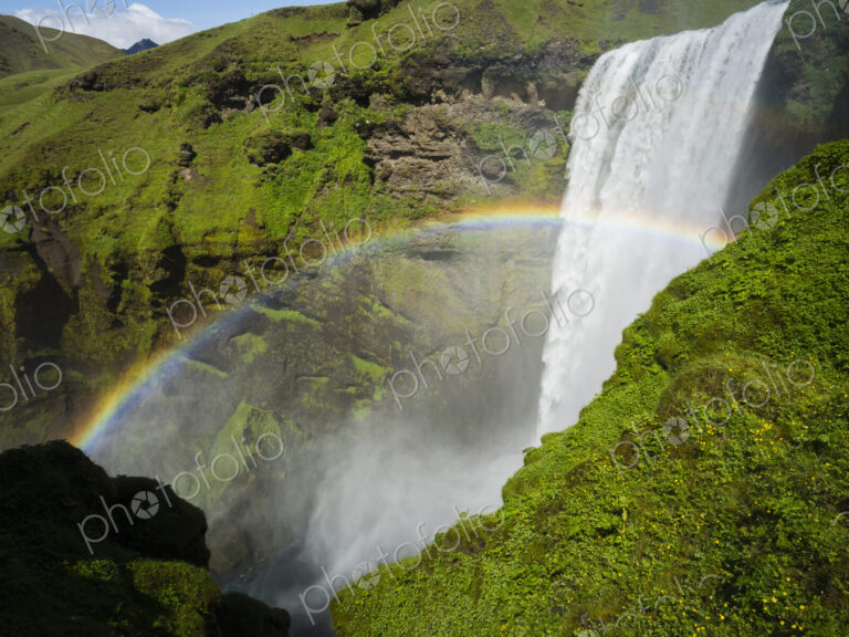 Skogafoss waterfall, a cascade over a sheer cliff, and a rainbow in the mist.