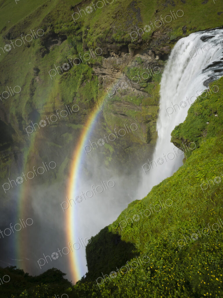 Skogafoss waterfall with a double rainbow in the mist and vapour rising from the water.
