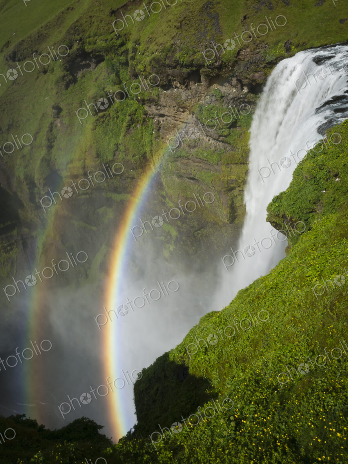 Skogafoss waterfall with a double rainbow in the mist and vapour rising from the water.