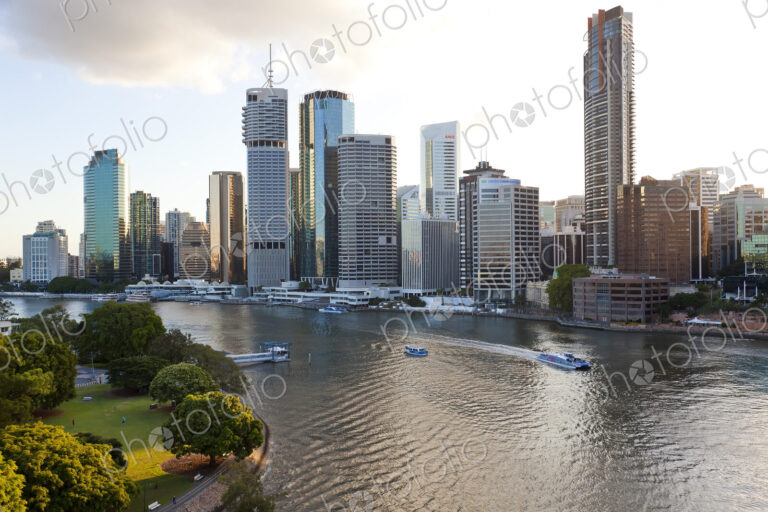 Skyline of city by the ocean, with skyscrapers and boats on the river.