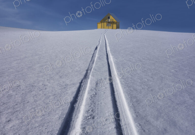 Sled tracks on hillside to yellow rural house in Estonia.