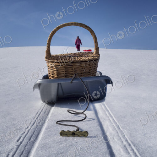 Sled transporting picnic basket over hilly snowy winter landscape