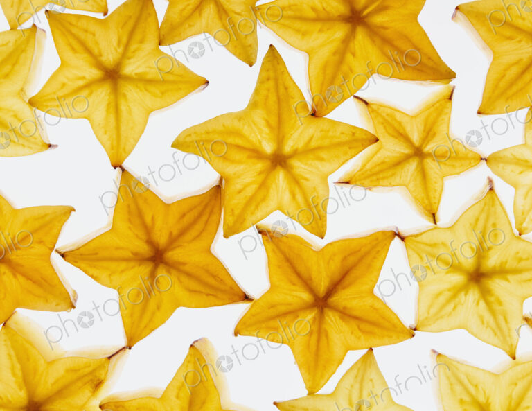 Slices of organic starfruit on a white background