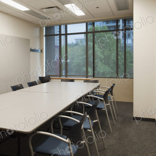 Small empty boardroom with a long rectangular table and chairs.