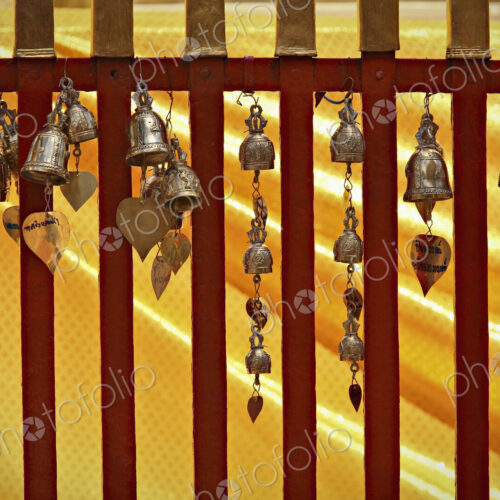 Small metal bells hanging from a railing in an ancient temple, Chang Mai Small metal bells hanging from a railing in an ancient temple, Chang Mai