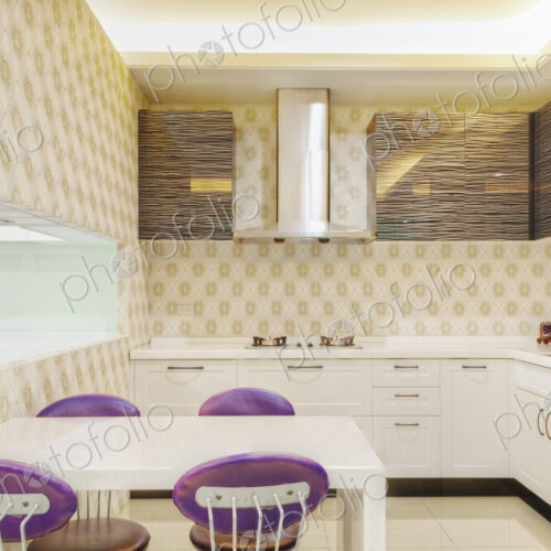Small modern kitchen with fitted microwave oven , white cupboards and patterned tiles.