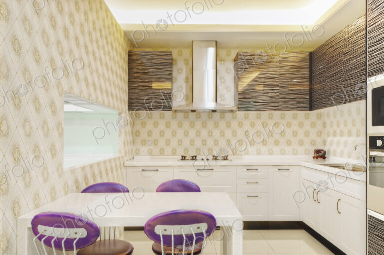 Small modern kitchen with fitted microwave oven , white cupboards and patterned tiles.