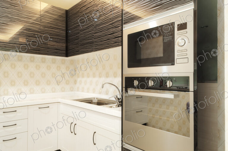 Small modern kitchen with fitted microwave oven, white cupboards and patterned tiles.