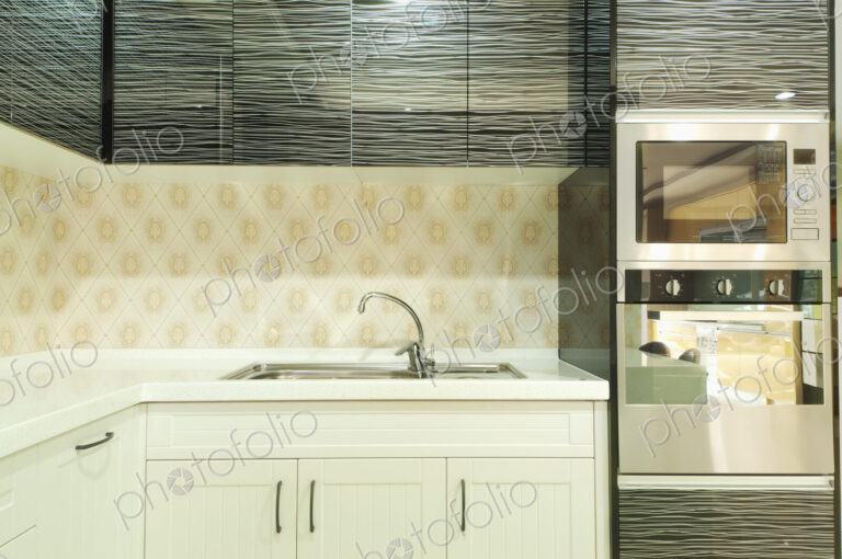 Small modern kitchen with fitted microwave oven , white cupboards and patterned tiles.