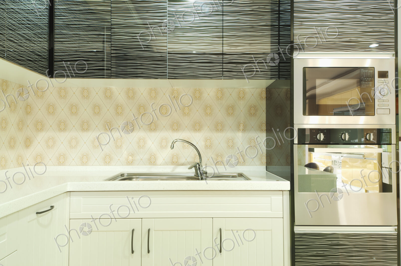Small modern kitchen with fitted microwave oven , white cupboards and patterned tiles.