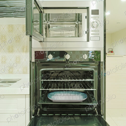 Small modern kitchen with fitted units and appliances and oven with an open door.