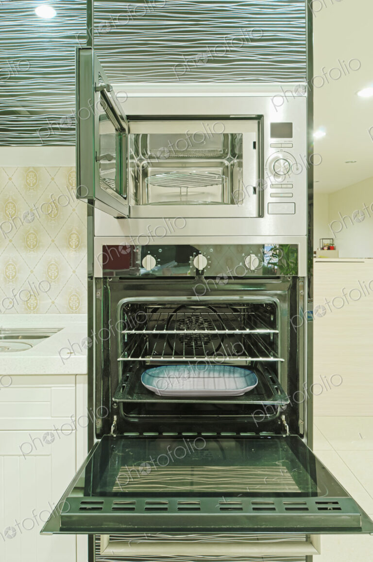 Small modern kitchen with fitted units and appliances and oven with an open door.