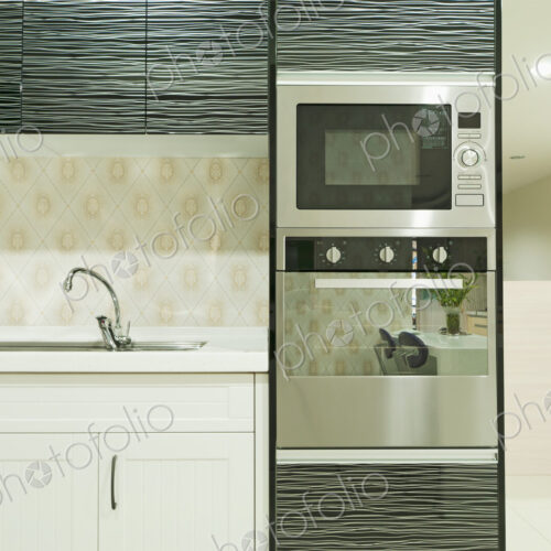 Small modern kitchen with fitted units and black glass cupboard doors, fitted…