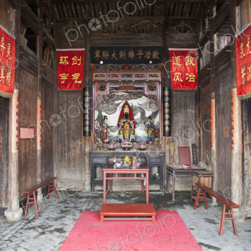 Small temple in Asia, red banners, altar with statues, incense burners
