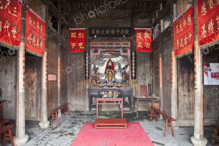 Small temple in Asia, red banners, altar with statues, incense burners