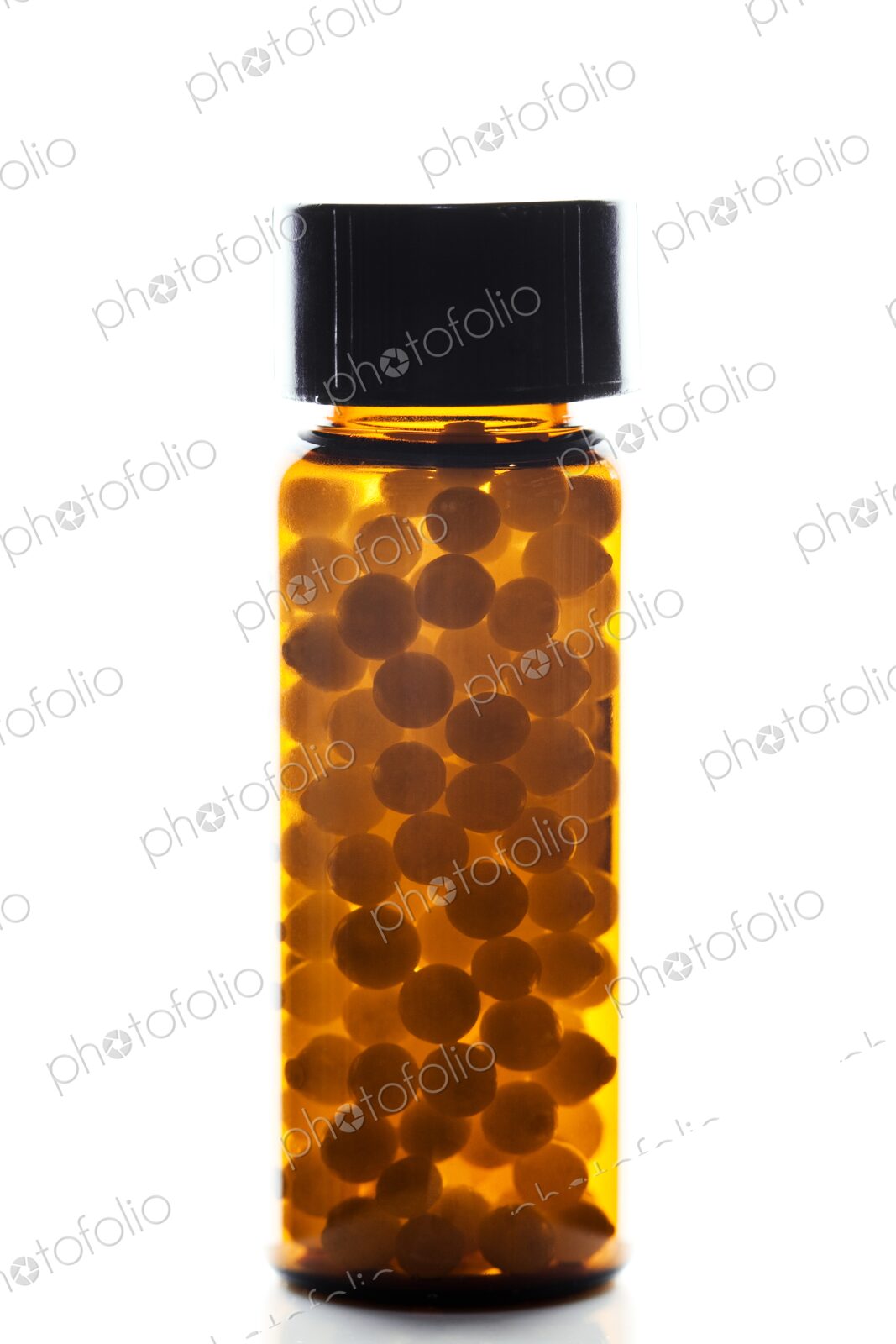 Small vial or container filled with homeopathic pills against a white background.