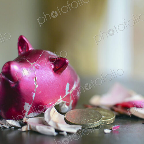 Smashed piggy bank with pounds on table.