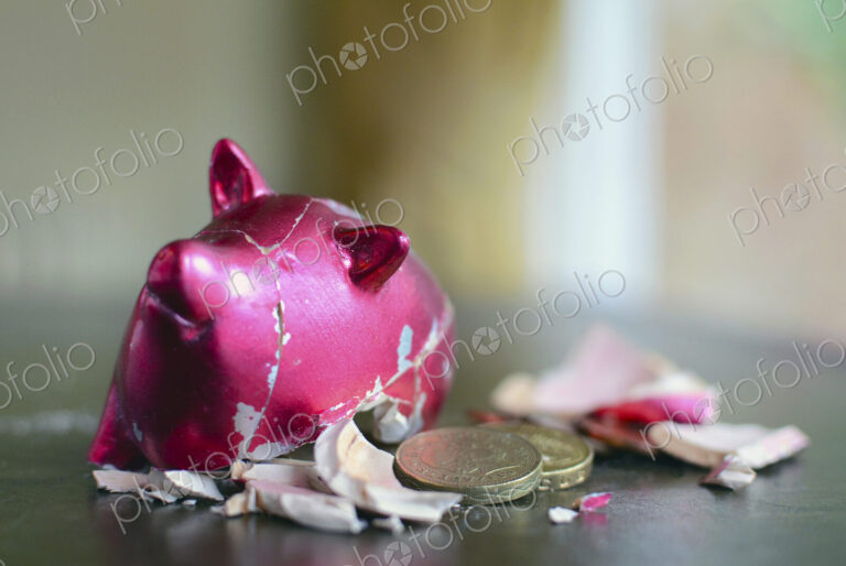 Smashed piggy bank with pounds on table.