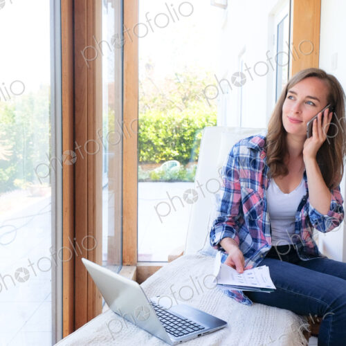 Smiling Caucasian woman holding paperwork and talking on cell phone Smiling Caucasian woman holding paperwork and talking on cell phone