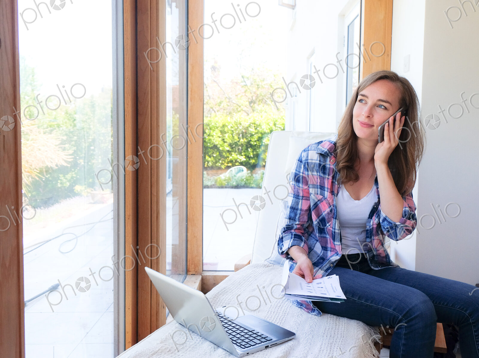 Smiling Caucasian woman holding paperwork and talking on cell phone