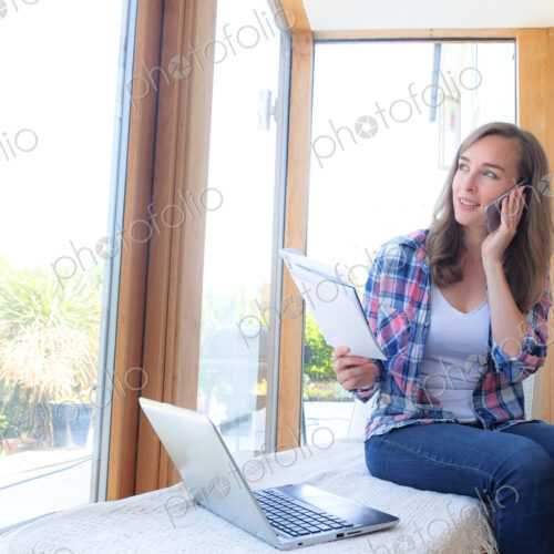 Smiling Caucasian woman holding paperwork and talking on cell phone Smiling Caucasian woman holding paperwork and talking on cell phone
