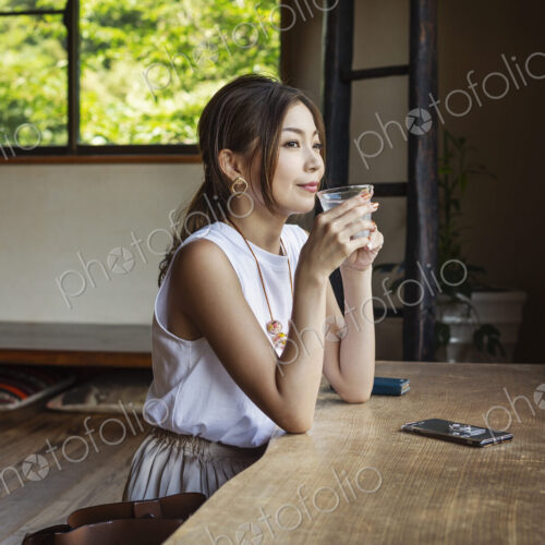 Smiling Japanese woman sitting at a table in a Japanese restaurant, drinking. Smiling Japanese woman sitting at a table in a Japanese restaurant, drinking.