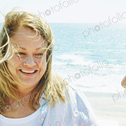 Smiling blond mature women standing by the ocean.