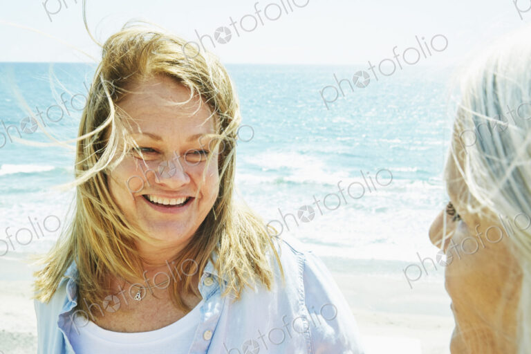 Smiling blond mature women standing by the ocean.