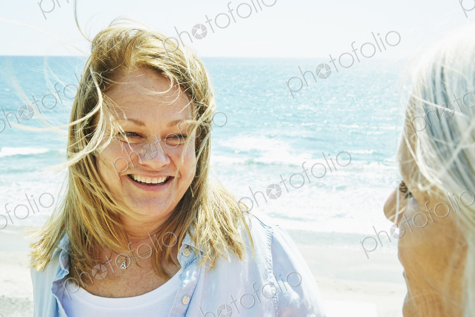 Smiling blond mature women standing by the ocean.