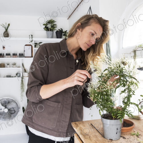 Smiling female owner of plant shop sitting on steps outside her store, a dog sitting… Smiling female owner of plant shop sitting on steps outside her store, a dog sitting…