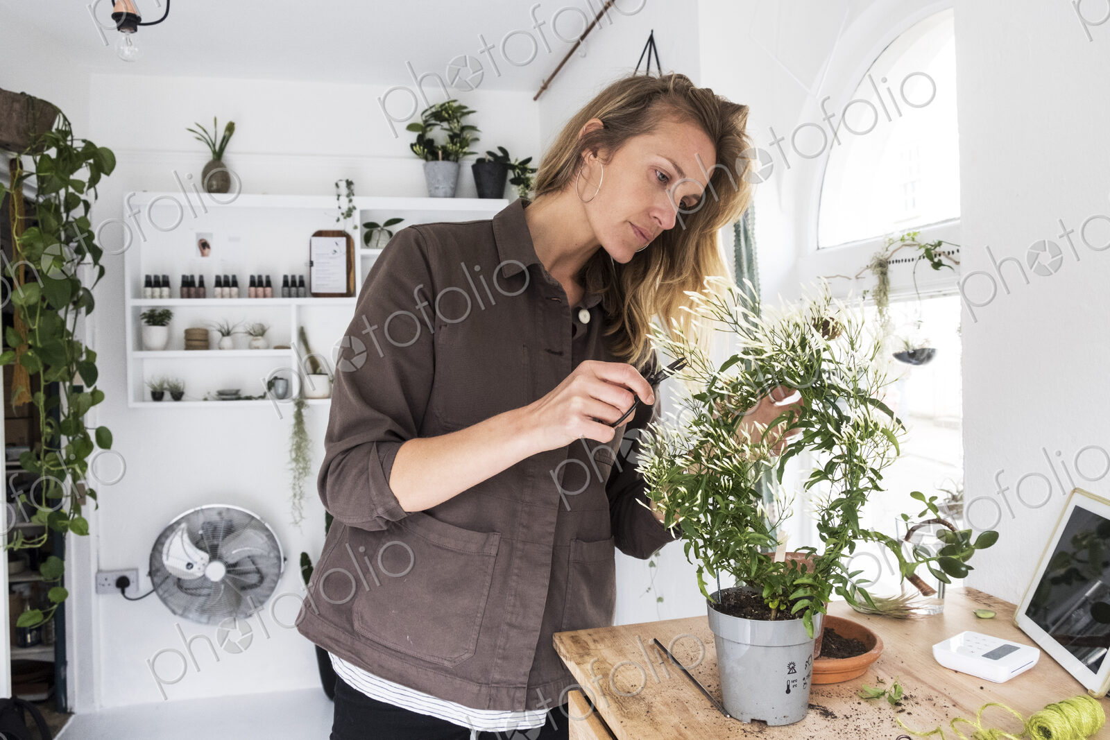 Smiling female owner of plant shop sitting on steps outside her store, a dog sitting…