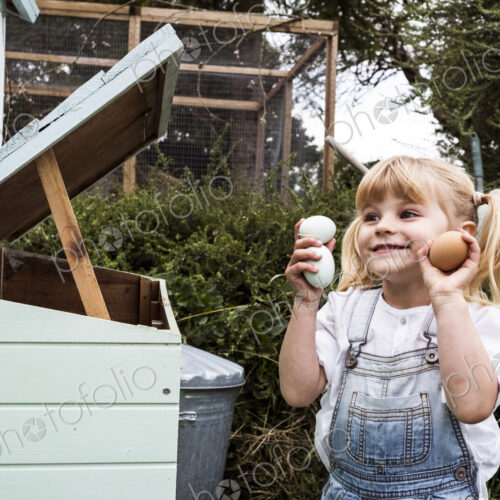 Smiling girl standing outdoors, holding three freshly laid eggs in her hands. Smiling girl standing outdoors, holding three freshly laid eggs in her hands.