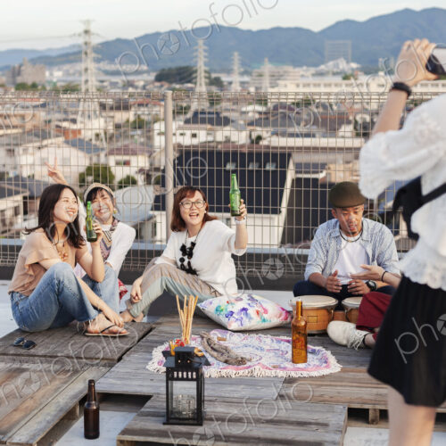 Smiling group of young Japanese men and women on a rooftop in an urban setting.