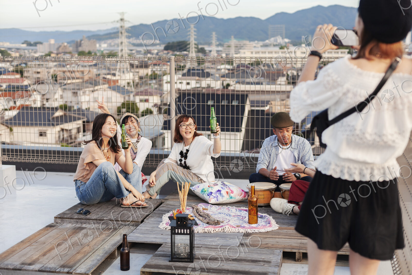 Smiling group of young Japanese men and women on a rooftop in an urban setting.