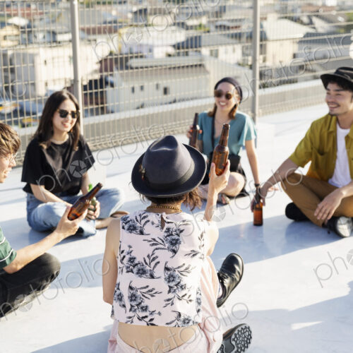 Smiling group of young Japanese men and women sitting on a rooftop in an urban setting. Smiling group of young Japanese men and women sitting on a rooftop in an urban setting.