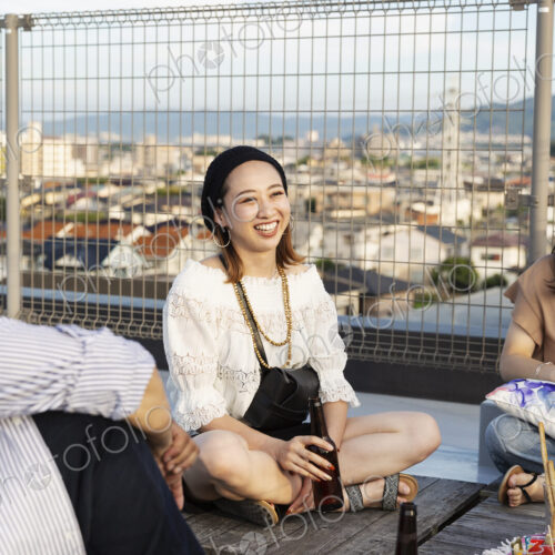 Smiling group of young Japanese men and women sitting on a rooftop in an urban setting. Smiling group of young Japanese men and women sitting on a rooftop in an urban setting.