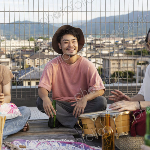 Smiling group of young Japanese men and women sitting on a rooftop in an urban setting. Smiling group of young Japanese men and women sitting on a rooftop in an urban setting.