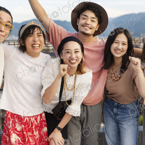 Smiling group of young Japanese men and women standing on a rooftop in an urban setting. Smiling group of young Japanese men and women standing on a rooftop in an urban setting.