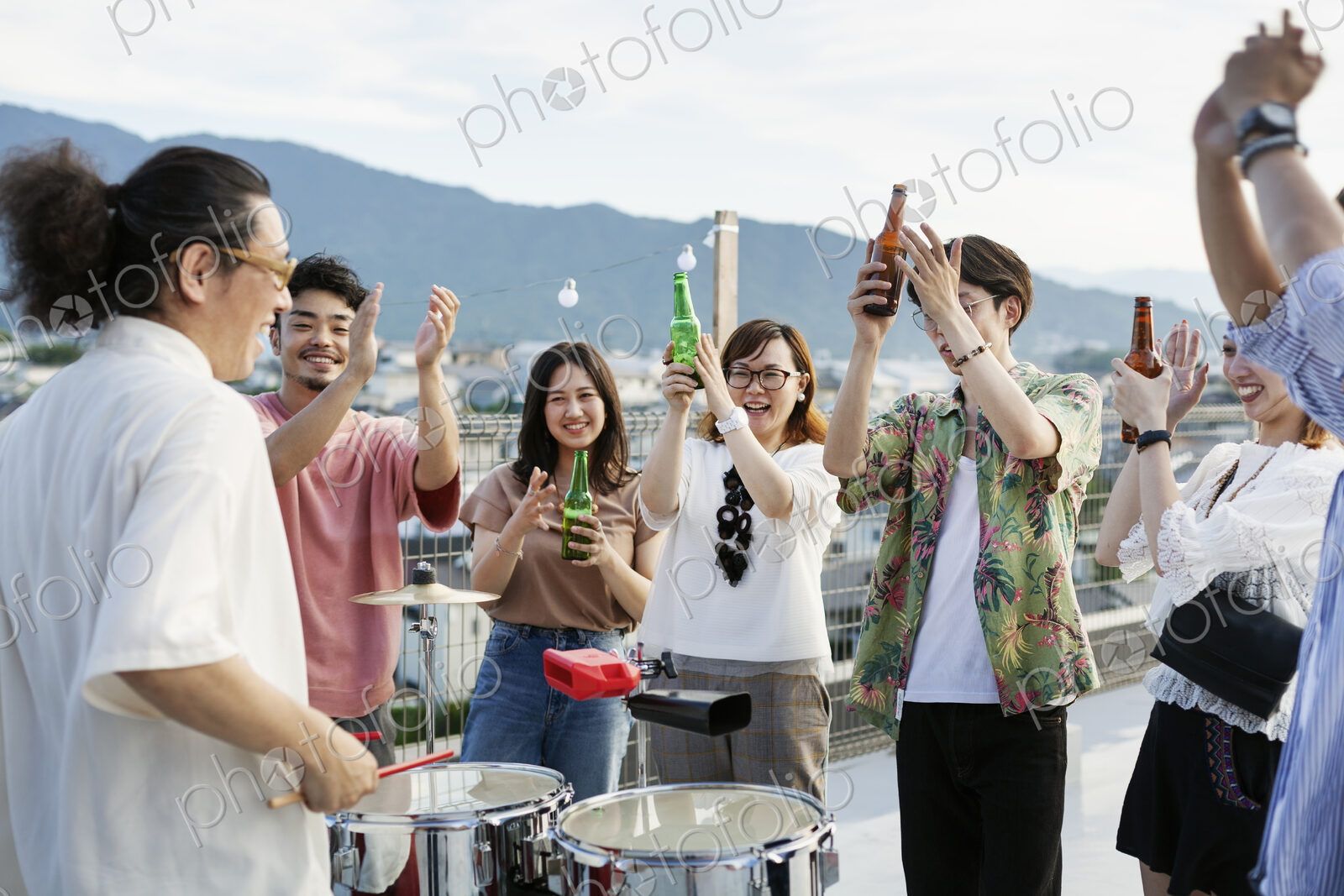 Smiling group of young Japanese men and women standing on a rooftop in an urban…