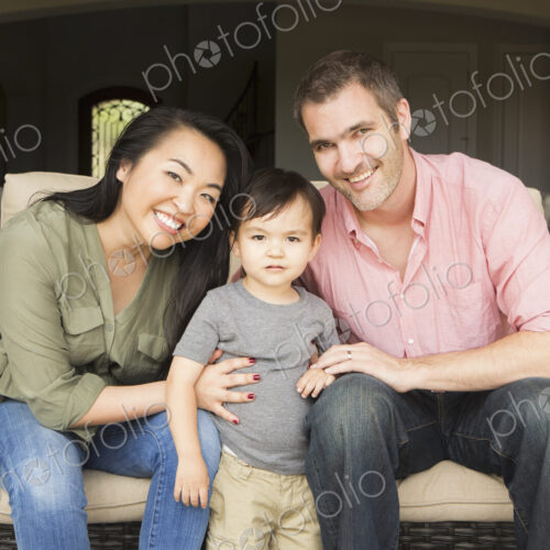 Smiling man and woman sitting side by side on a sofa, posing for a picture with their… Smiling man and woman sitting side by side on a sofa, posing for a picture with their…