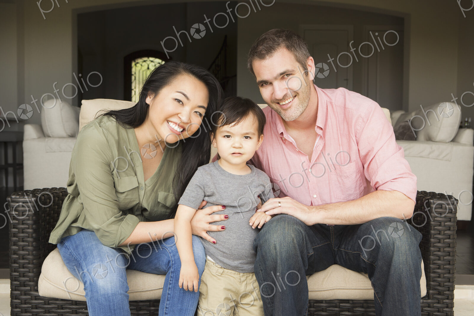 Smiling man and woman sitting side by side on a sofa, posing for a picture with their…