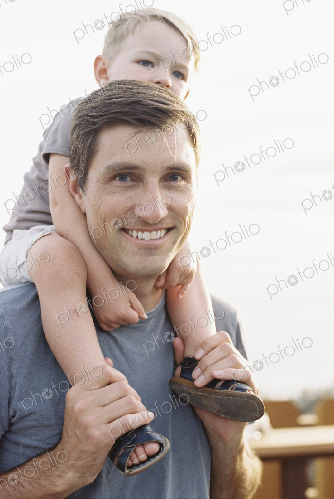 Smiling man carrying his young son on his shoulders.