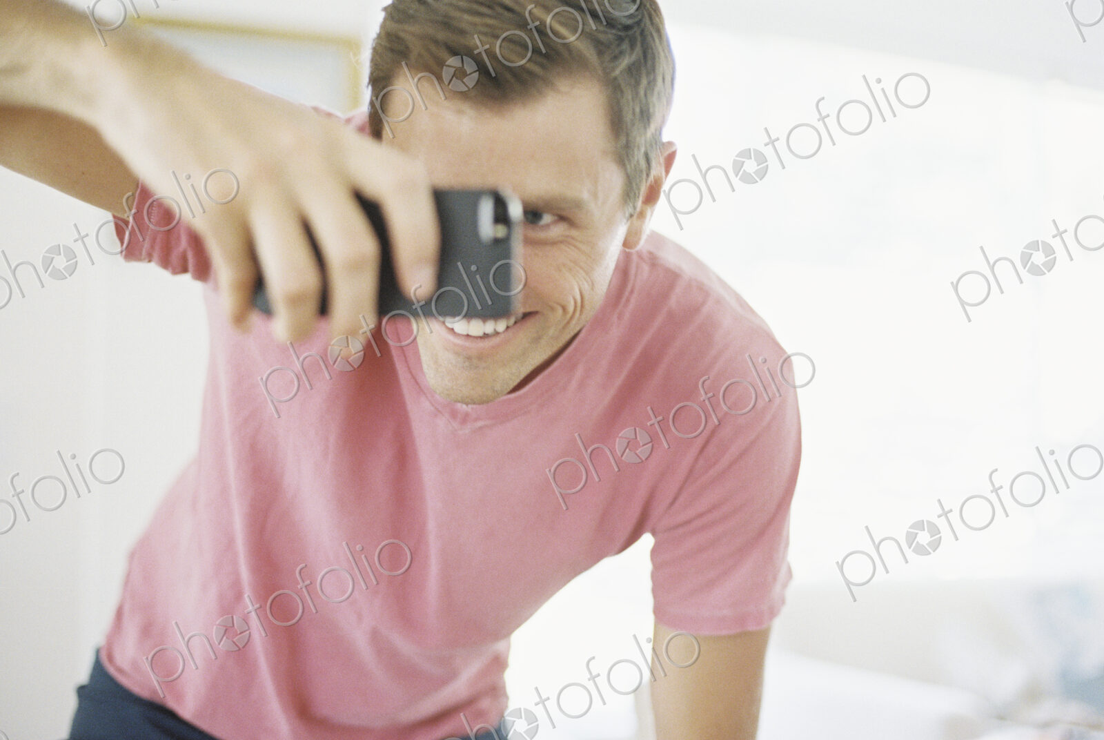 Smiling man taking a picture with a smart phone.