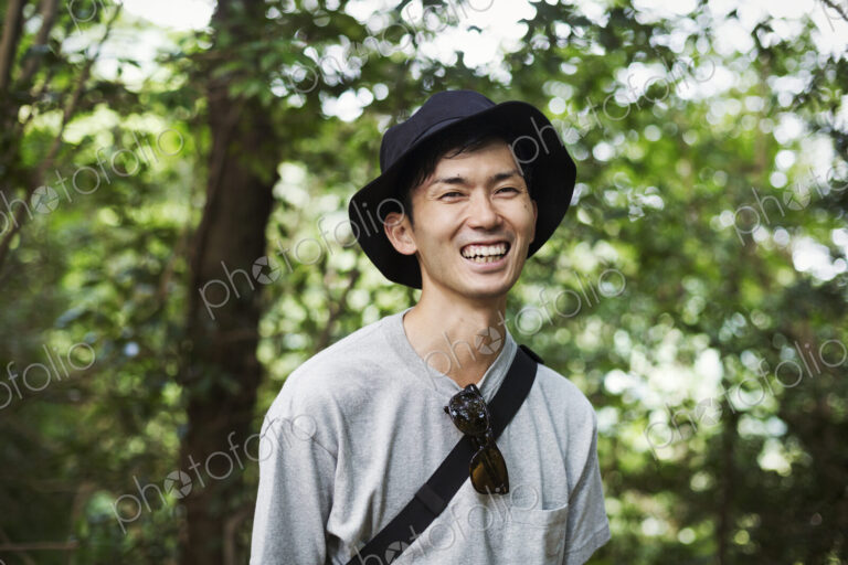 Smiling man wearing a hat standing in a forest.