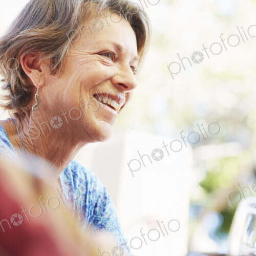 Smiling mature woman with blond hair sitting outdoors.
