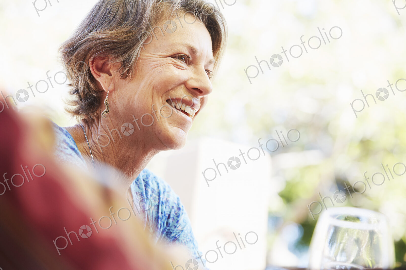 Smiling mature woman with blond hair sitting outdoors.
