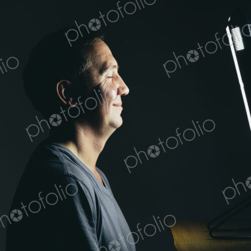 Smiling middle aged man sitting in front of a light therapy box. Smiling middle aged man sitting in front of a light therapy box.