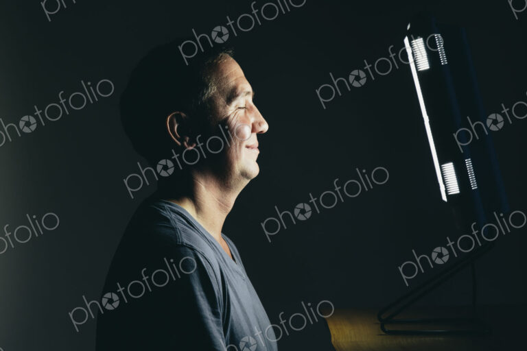 Smiling middle aged man sitting in front of a light therapy box.