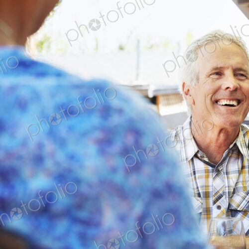 Smiling senior man with grey hair sitting outdoors.