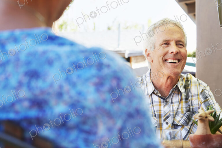 Smiling senior man with grey hair sitting outdoors.